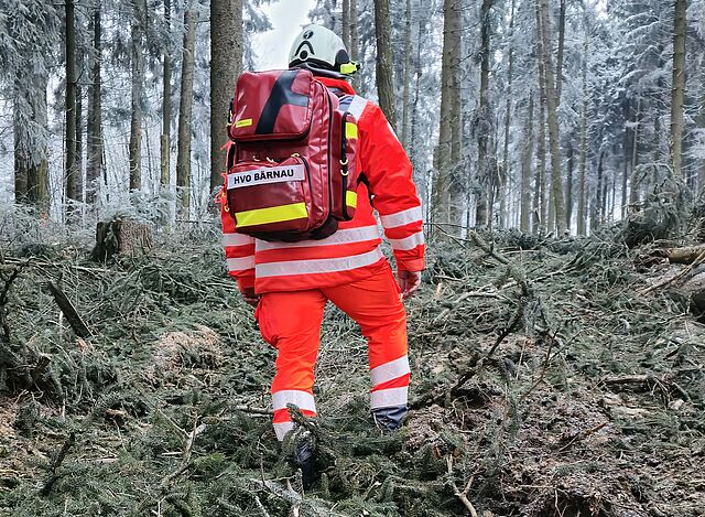 Einsatzkraft des HvO Bärnau geht im unwegsamen Gelände mit seiner Notfallausrüstung zum Einsatzort.